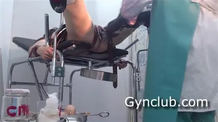 Eine gebundene Patientin in einem Gynäkologen stöhnt, wenn ein Arzt ihre Muschi fingert